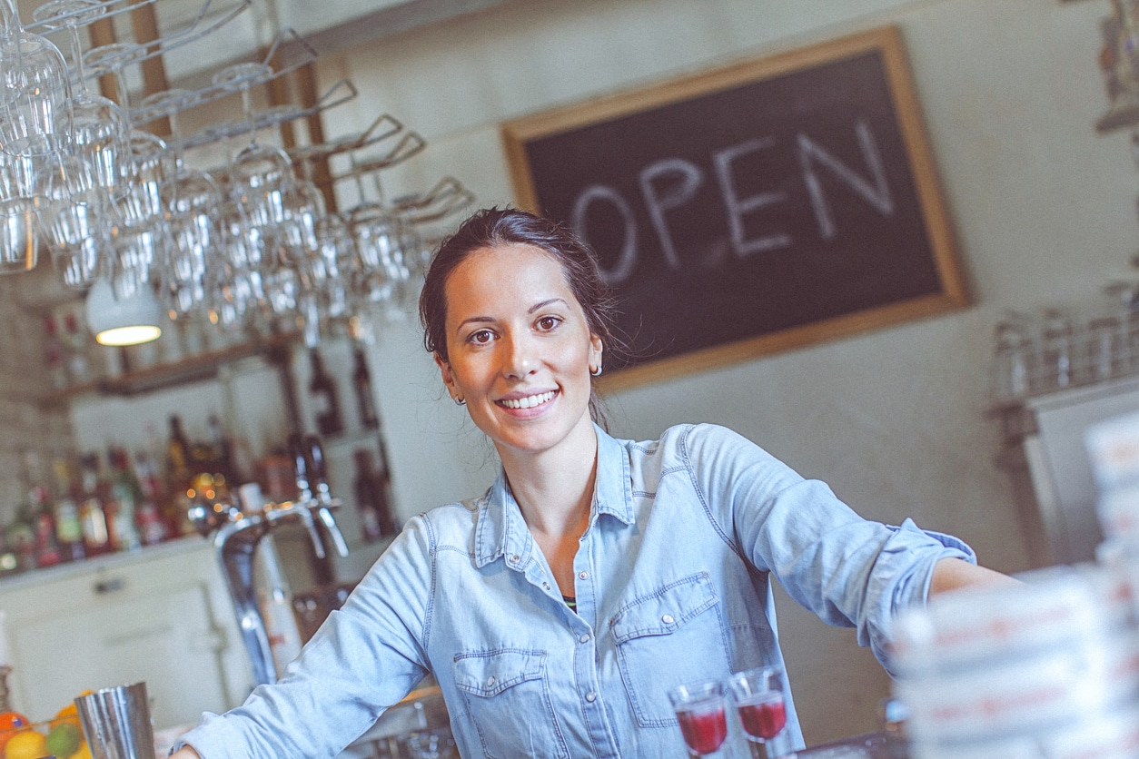 Young happy female bar owner posing at the bar counter